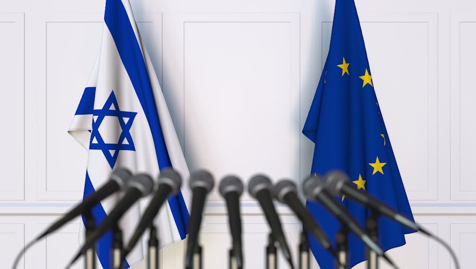 EU and Israeli flags behind a row of microphones. 