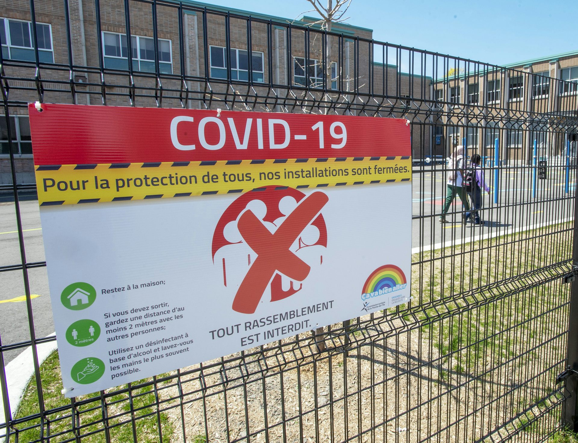 A sign says 'COVID-19' on a school fence.