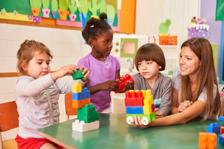 Children and nursery worker playing with blocks