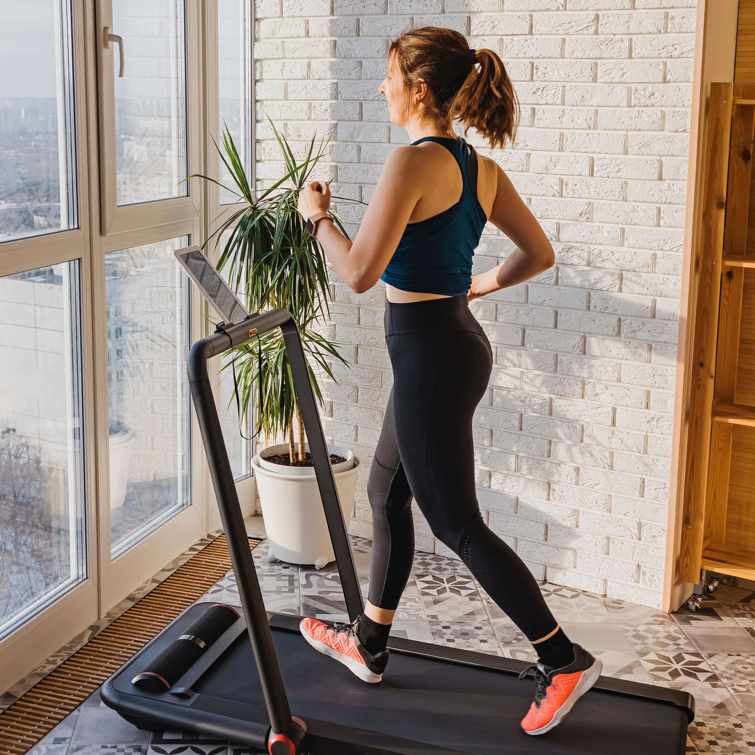 A woman walking on a treadmill at home.