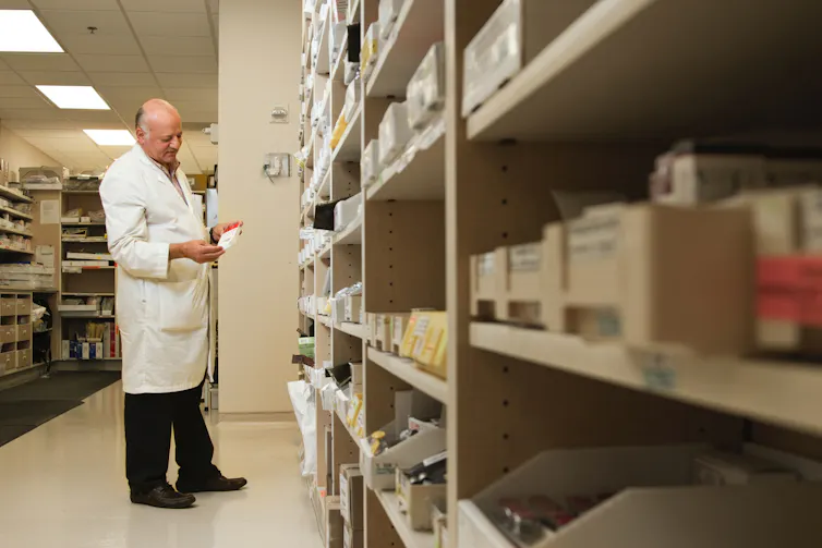 Farmacêutico olha o rótulo da caixa de medicamentos