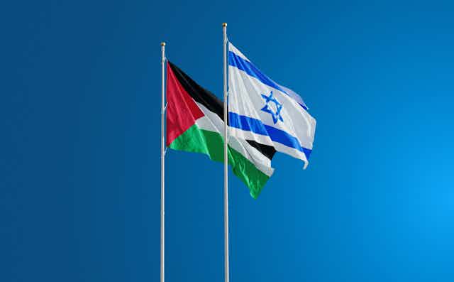 Una bandera palestina y una bandera israelí ondean al viento.