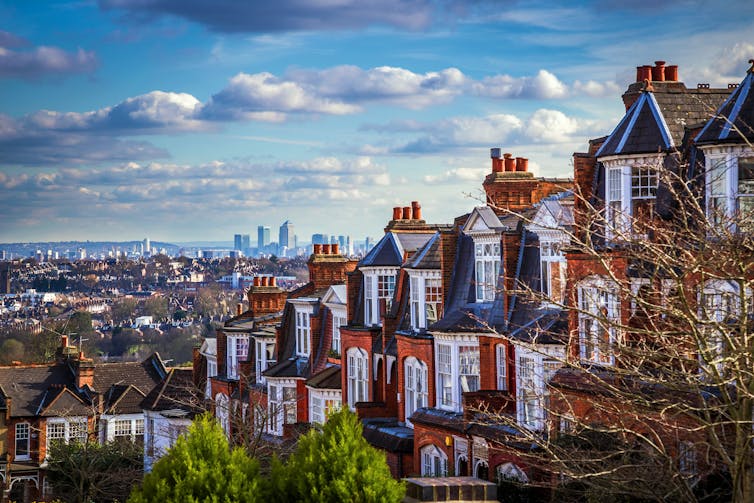 Panoramic skyline view of London with traditional brick houses in the foreground.
