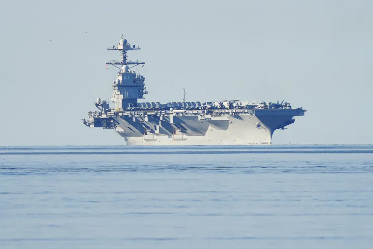 An aircraft carrier with fighter jets on at sea.