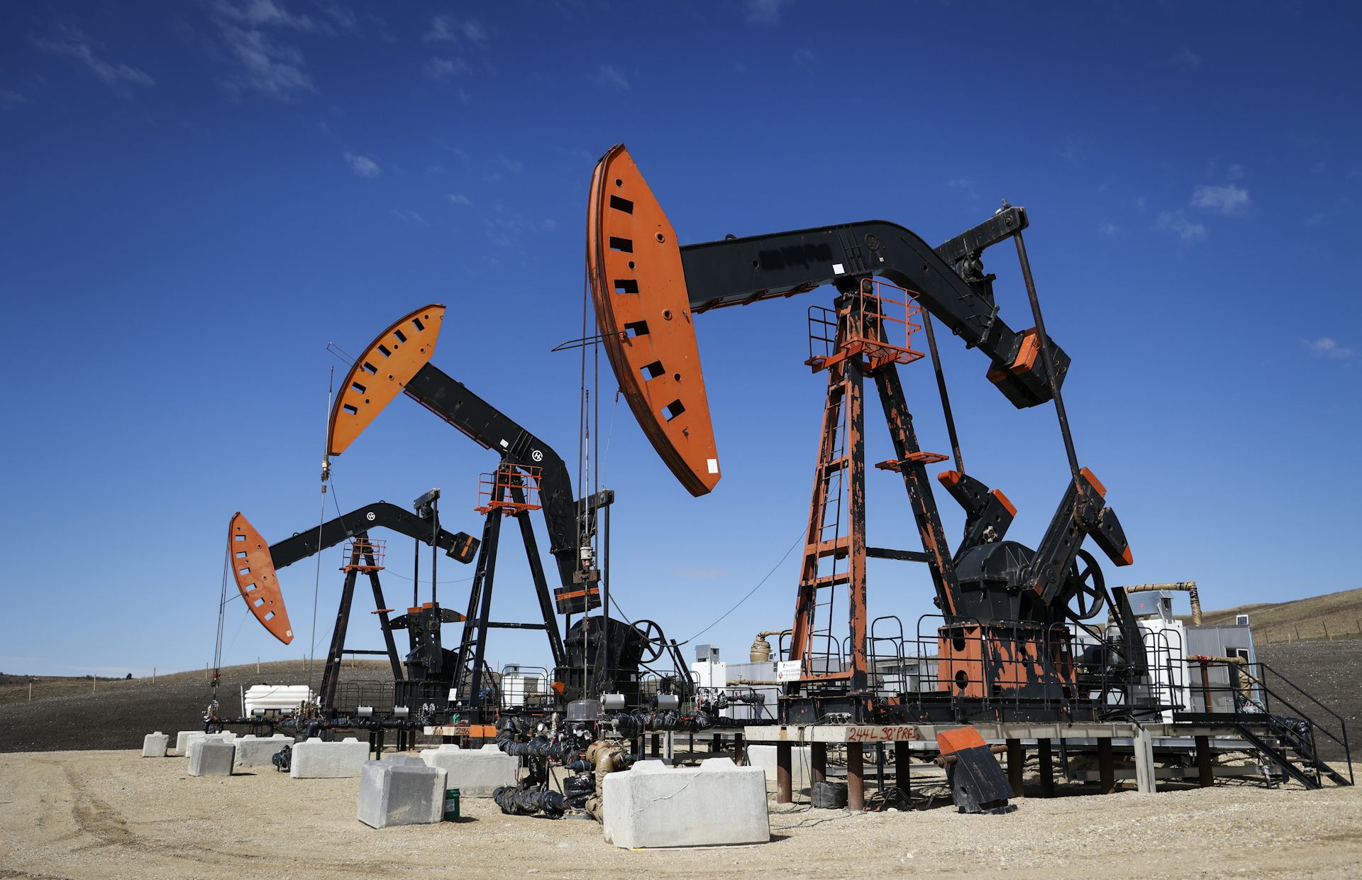 A row of pumpjacks seen against a clear blue sky.