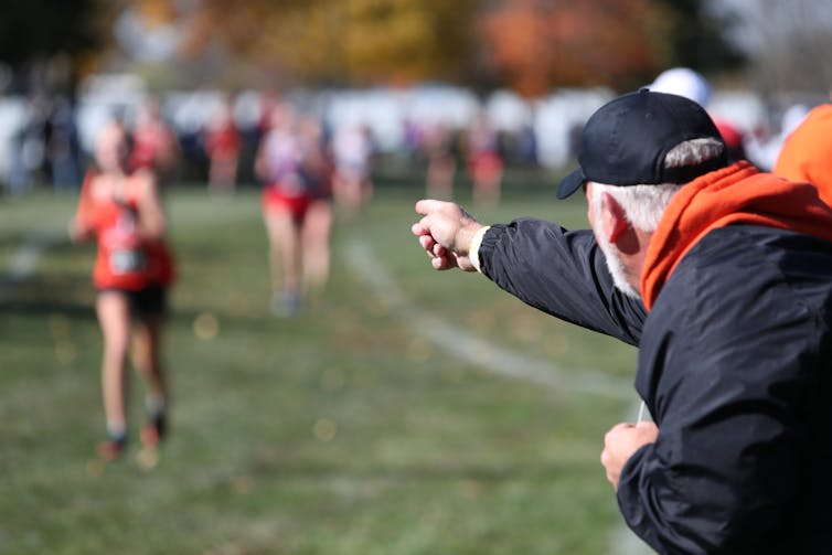 A man yelling from the sidelines of a running race