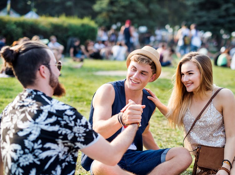 Three young people socialising at a festival.