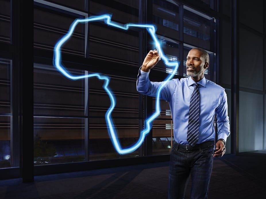A photograph of a businessman in a light blue shirt and a dark blue striped tie painting a map of the African continent in light