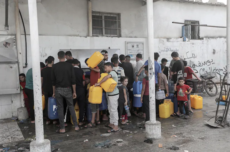 People with jerrycans queue for water.