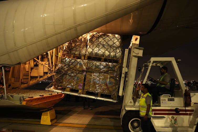 A forklift truck loads a pallet of aid parcels on to an aircraft.