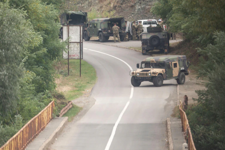 Three trucks at the side of the road.