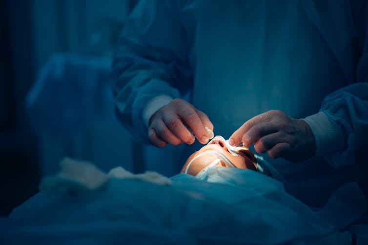 Un cirujano realizando una rinoplastia a un paciente.