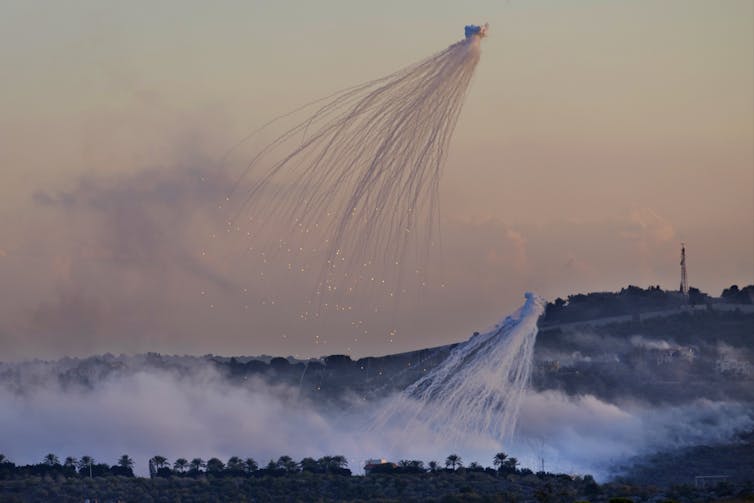 el humo de un proyectil explosionado oscurece el paisaje con un pueblo al fondo