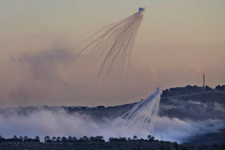el humo de un proyectil explosionado oscurece el paisaje con un pueblo al fondo