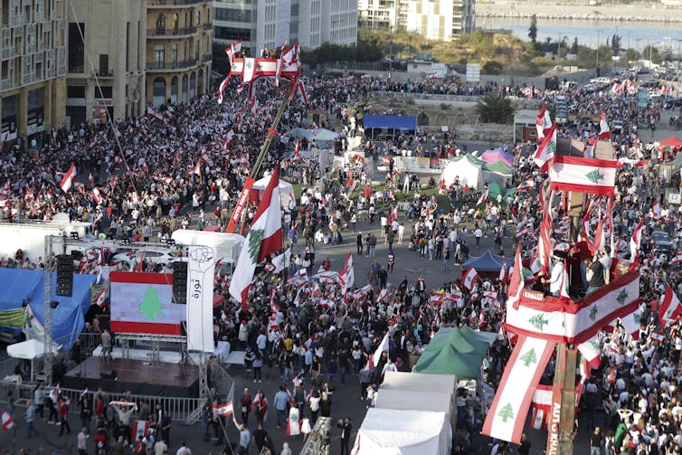 many protesters march in downtown beirut carrying lebanese flags