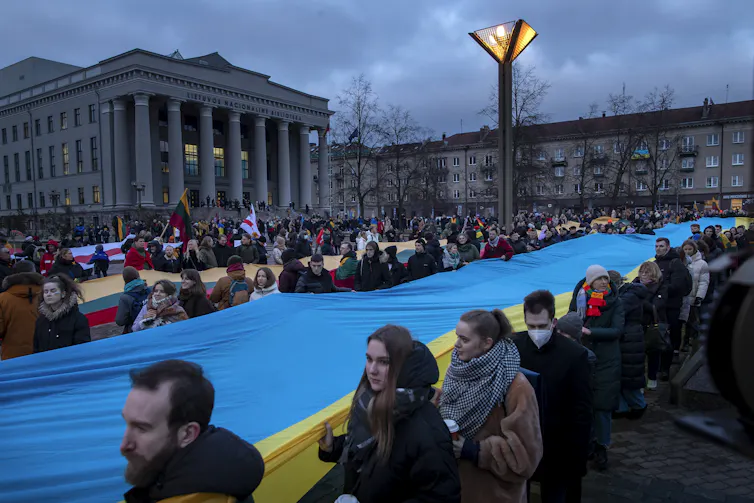 People carry a giant blue and yellow flag.
