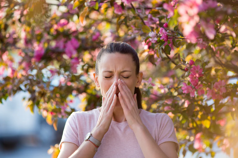 woman outside near blossoming tree looks about to sneeze