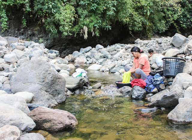 A woman doing her laundry next to a river.