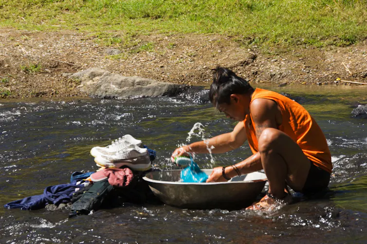 A man washing his clothes in a river.