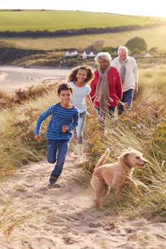 Photo d’une famille en promenade en bord de mer, avec un jeune chien.