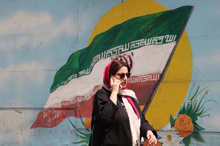 Une femme iranienne passe devant un drapeau iranien peint sur un mur dans une rue de Téhéran