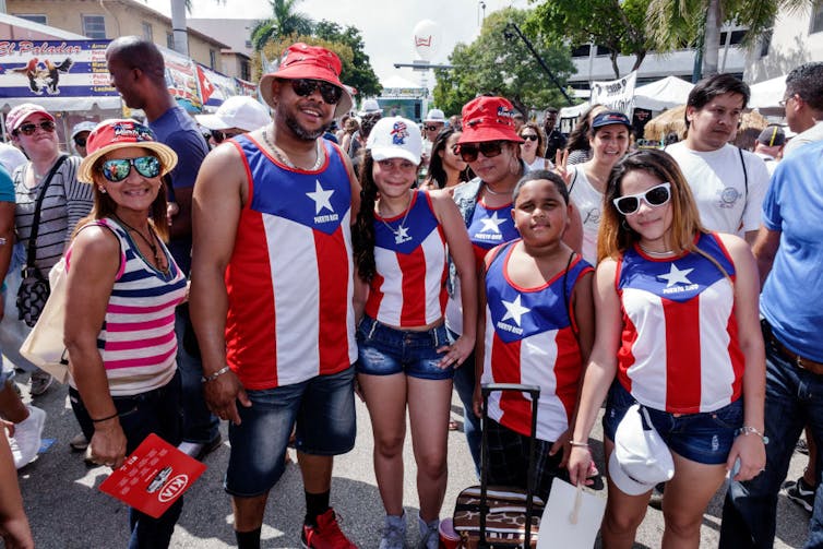 Family poses wearing red and blue outfits in the style of the Puerto Rican flag.