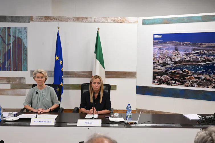 Ursula Von der Leyen and Giorgia Meloni sitting together at a desk for a press conference.