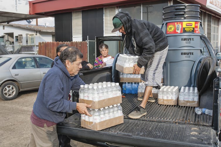 Residents of East Porterville, California, lift pallets of bottled water out of the back of a truck.