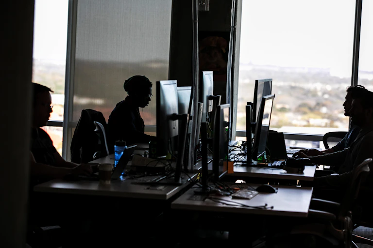 three people in an office work at computers