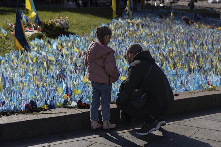 A man and young girl stand near a collection of blue and yellow flags.