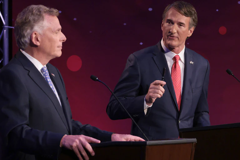 Two middle aged white man are dressed in business suits and are standing behind lecturns.