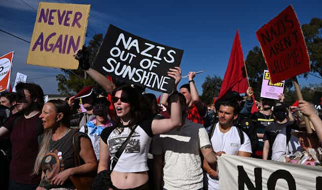 A crowd of protestors against Nazis holding signs