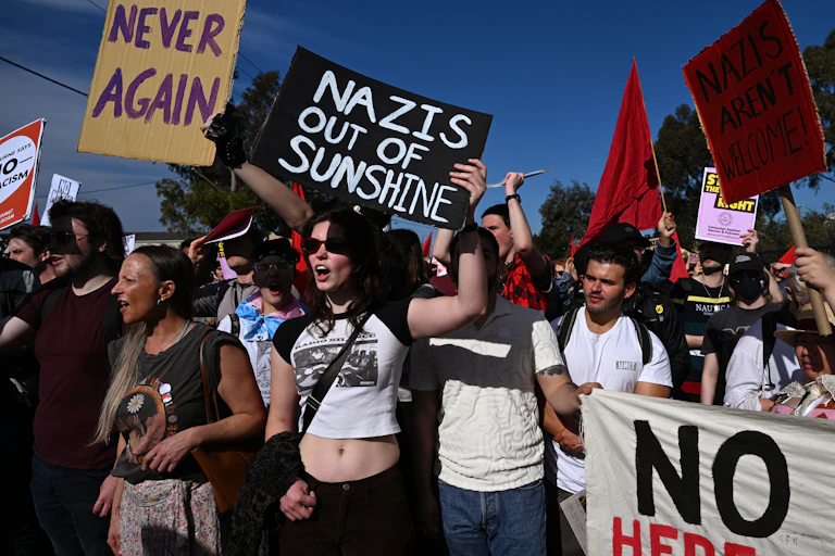 A crowd of protestors against Nazis holding signs