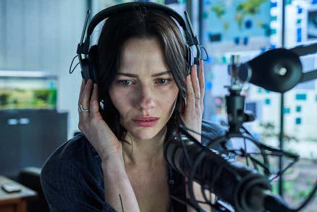 Woman wearing headphones staring into microphone