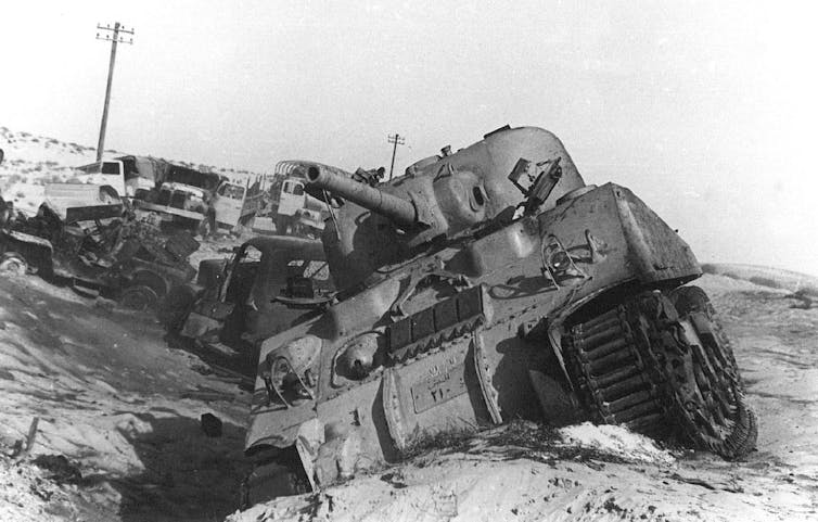 A crippled tank with other damaged military vehicles.
