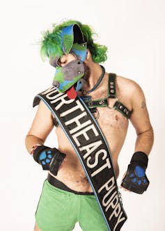 Man wearing pup hood and leather harness.