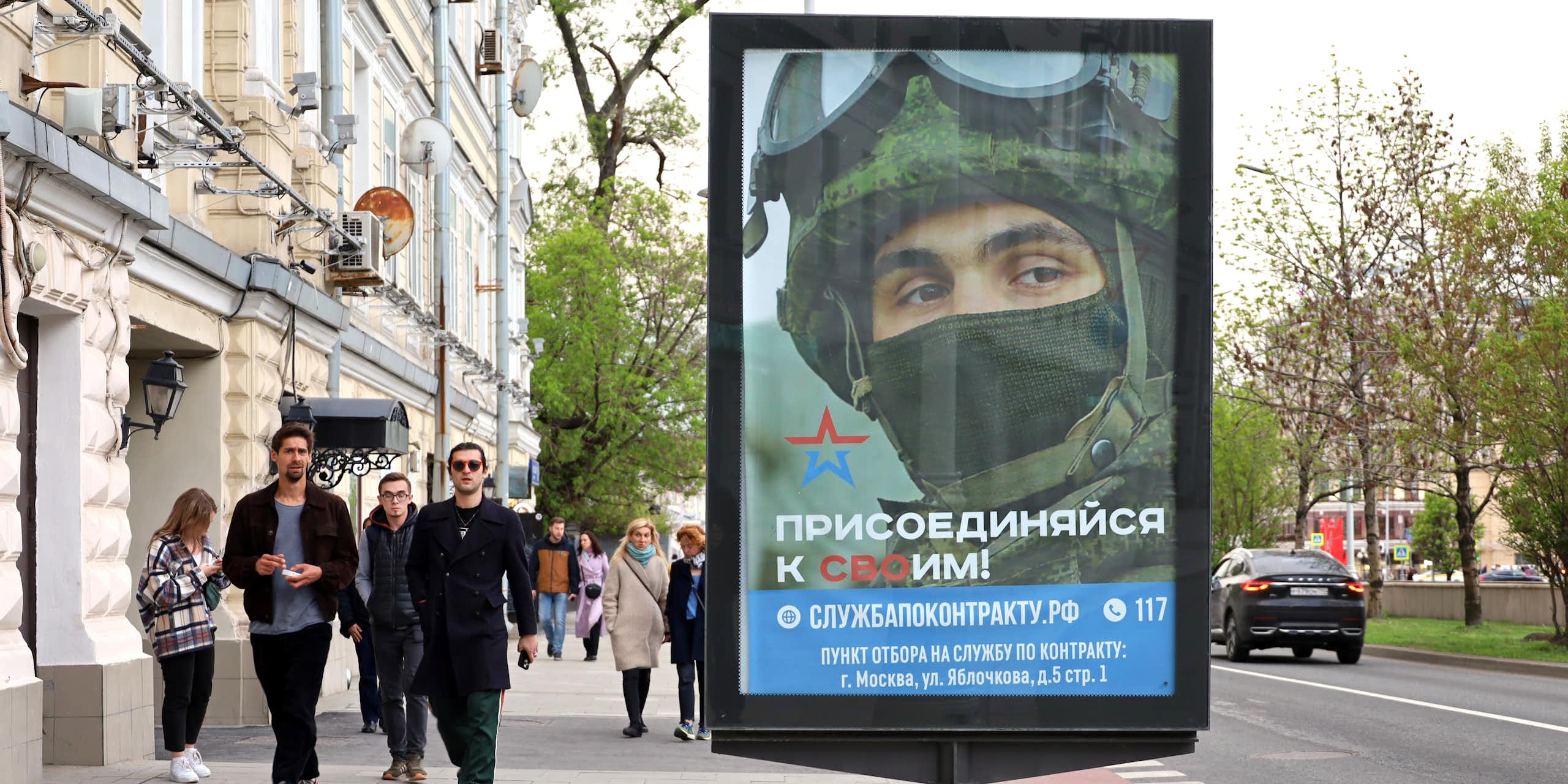 Des passants dans une rue de Moscou, devant une affiche de recrutement de l'armée russe