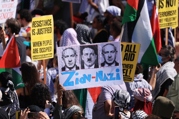 Demonstrators carrying signs that include one equating Zionism to Nazism.