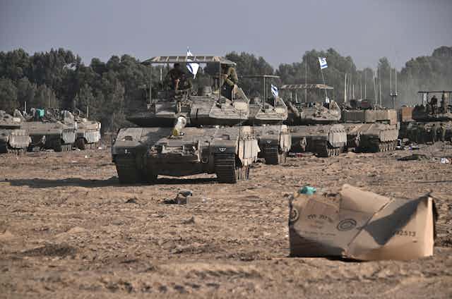 A group of tanks rolls over rough ground.