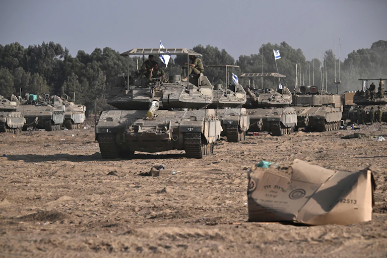 A group of tanks rolls over rough ground.