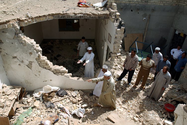 People gather at the collapsed corner of a building.