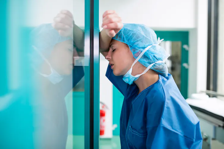 Exhausted doctor leans up against a wall