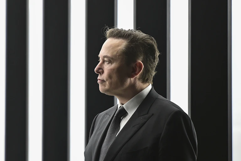 Man in suit stands in front of background made of vertical lights