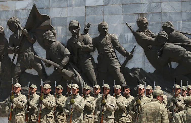 Soldiers stand before a World War I statue.
