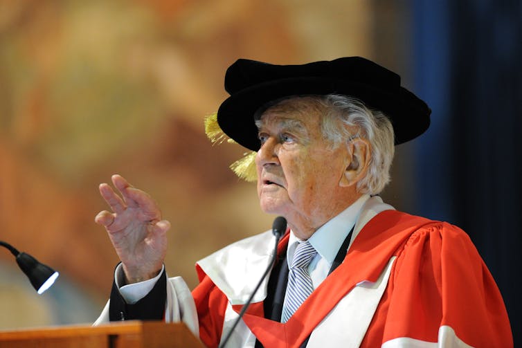 Former Prime Minister Bob Hawke speaks at a lecturn in academic regalia.