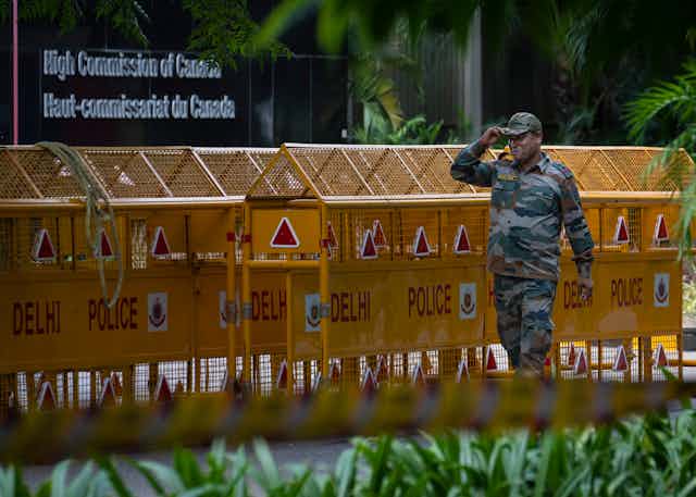 A soldier stands outside yellow police barricades.