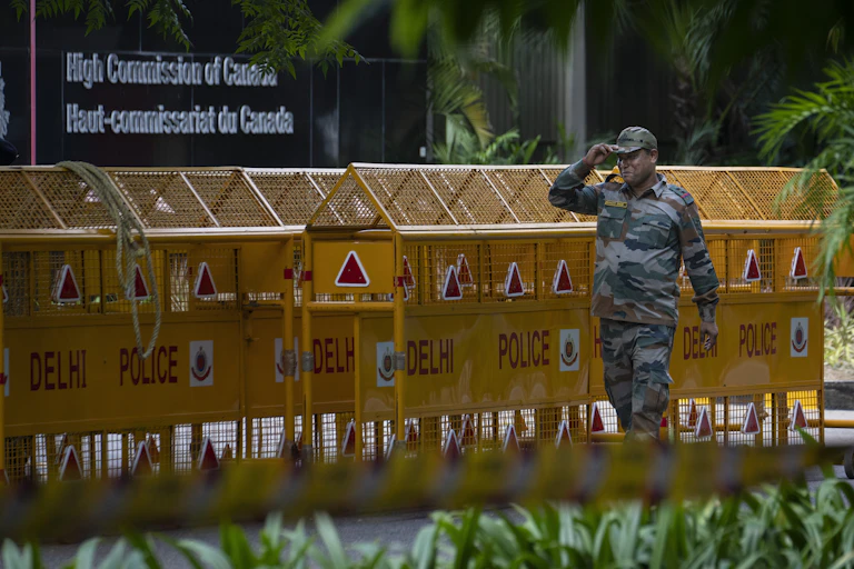 A soldier stands outside yellow police barricades.