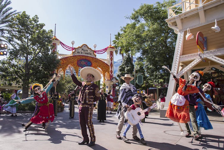 People in costumes dancing with characters inspired by Disney and Pixar's Coco.