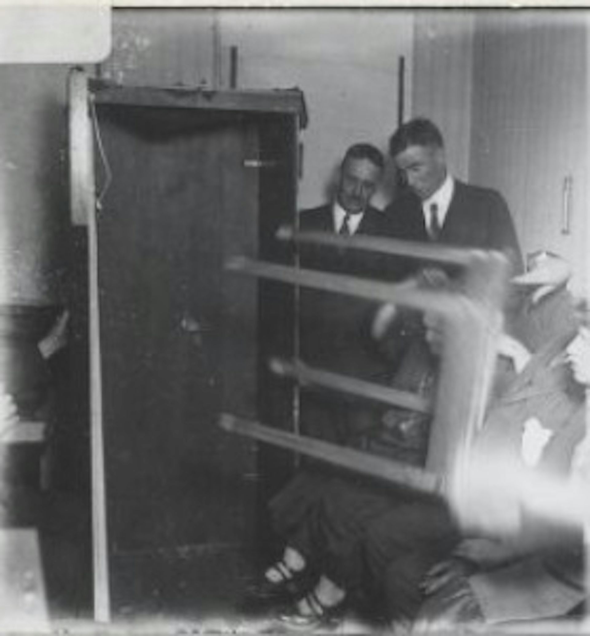 Men in suits seen near a table on its side.