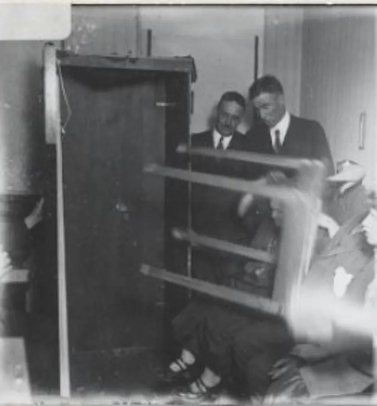 Men in suits seen near a table on its side.